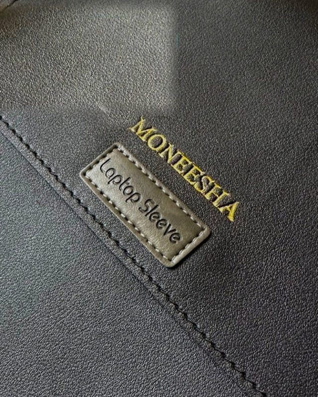 A name laser engraved in gold on a black leather Chemistors laptop sleeve